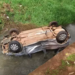 Condutor invade sinal vermelho, colide em Jeep e vai parar dentro de córrego